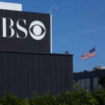 CBS logo on a building with an American flag in the background