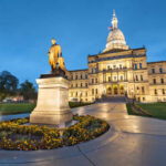 Statue in front of a state capitol building at dusk