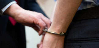 A close-up of a person being handcuffed by an officer