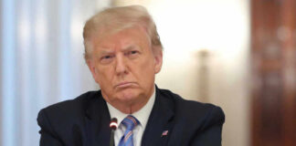 A serious-looking man in a suit with arms crossed during a meeting