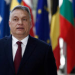 A political leader standing in front of various national flags