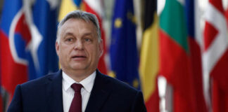 A political leader standing in front of various national flags