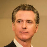 A man in business attire with a serious expression, captured in a medium shot