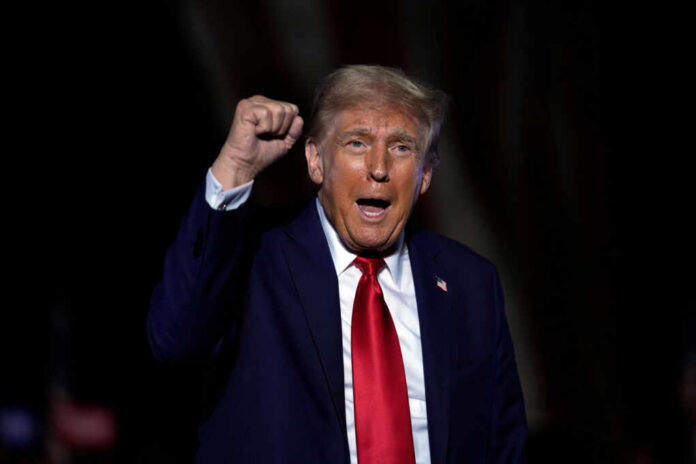 A man in a suit passionately speaking at a rally with a raised fist