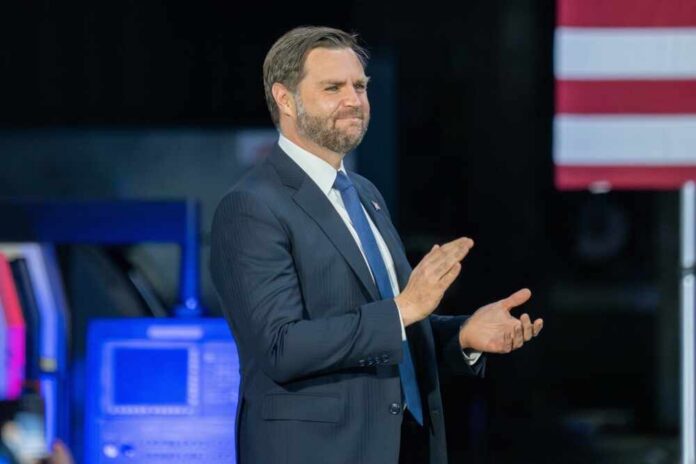 Man in a suit applauding at a political event with an American flag in the background