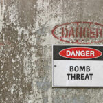 Warning sign indicating a bomb threat on a weathered wall