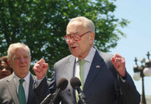 A politician speaking passionately at a press conference with microphones in front