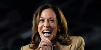 A woman in formal attire smiling broadly while speaking at a podium