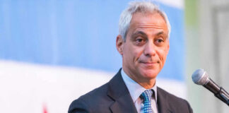 A man in a suit speaking at a podium with a microphone