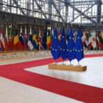 Flags of European countries displayed in a modern hall with a red carpet