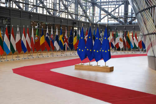 Flags of European countries displayed in a modern hall with a red carpet