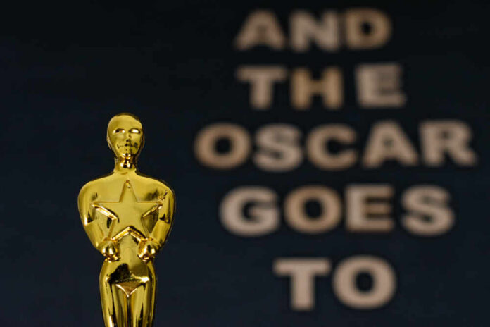Close-up of a golden Oscar statuette with text in the background