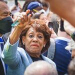 A woman at a political rally raising her hand in a crowd