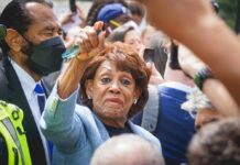 A woman at a political rally raising her hand in a crowd