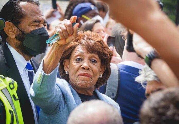 A woman at a political rally raising her hand in a crowd