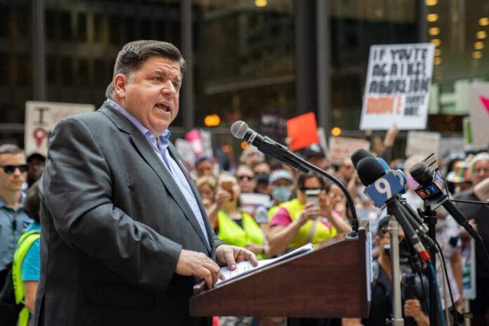 shutterstock_2211418655.jpg A speaker addressing a crowd at a political rally with protest signs in the background