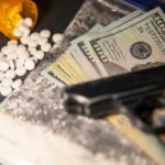 A handgun, cash, and prescription pills scattered on a surface