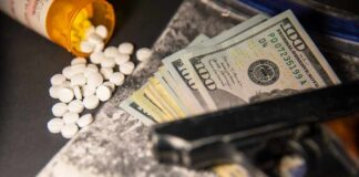 A handgun, cash, and prescription pills scattered on a surface