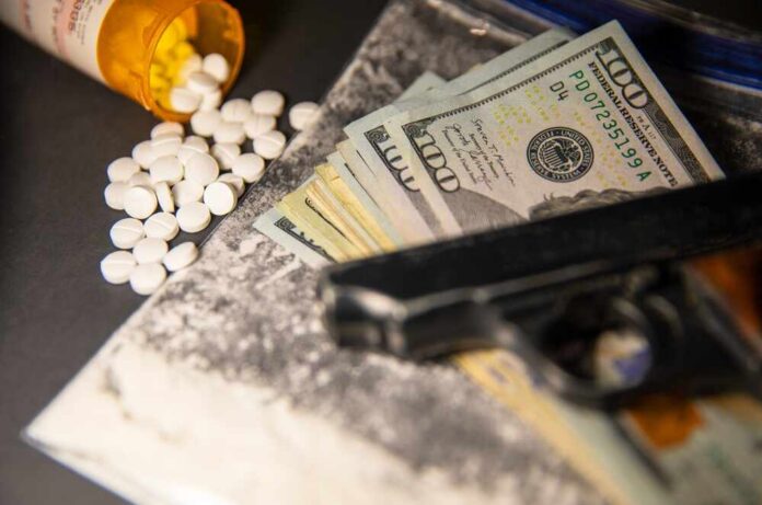 A handgun, cash, and prescription pills scattered on a surface