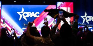 Paxton’s CPAC Triumph Exposes Republican Civil War Audience members at a CPAC event holding phones and flags