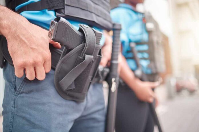 shutterstock_2328436969.jpg Two security personnel in tactical gear, one with a visible firearm