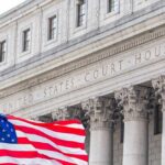 Facade of a United States courthouse with an American flag in the foreground