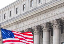 Facade of a United States courthouse with an American flag in the foreground