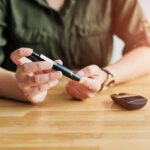 Person using a blood glucose meter and a pen device for diabetes management