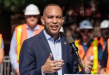 A man speaking at a podium with construction workers in the background