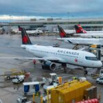Air Canada planes parked at an airport terminal with ground crew working