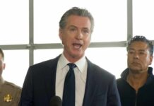 Politician delivering a speech at a press conference with officials in the background