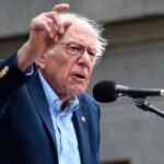A man passionately speaking at a microphone during a rally
