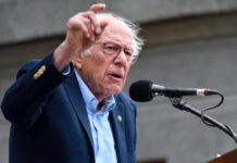 A man passionately speaking at a microphone during a rally