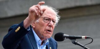 A man passionately speaking at a microphone during a rally