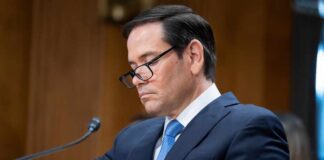 Individual in a suit reviewing documents during a senate hearing