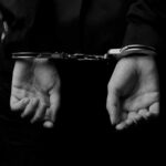 Hands in handcuffs against a dark background