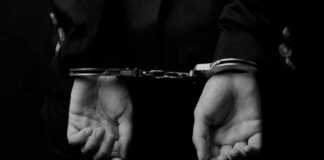 Hands in handcuffs against a dark background