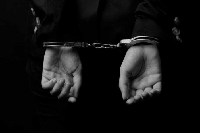 Hands in handcuffs against a dark background
