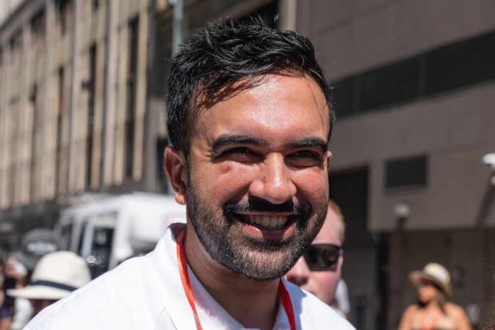 A smiling man in a casual white shirt standing outdoors