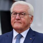 A senior political figure in formal attire with a serious expression