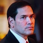 A serious-looking man in formal attire with a focused gaze