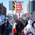 Crowd of protesters holding signs at a rally against ICE