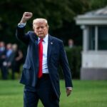 A political figure walking outdoors with a raised fist