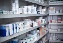 Shelves filled with various medication boxes and containers in a pharmacy