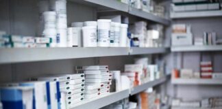Shelves filled with various medication boxes and containers in a pharmacy