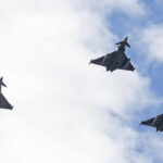 Three fighter jets flying in formation against a cloudy sky