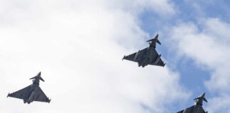 Three fighter jets flying in formation against a cloudy sky
