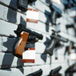 A variety of handguns displayed on a wall with price tags