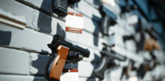 A variety of handguns displayed on a wall with price tags
