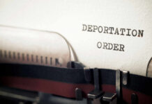 Close-up of a typewriter with a paper showing the words DEPORTATION ORDER
